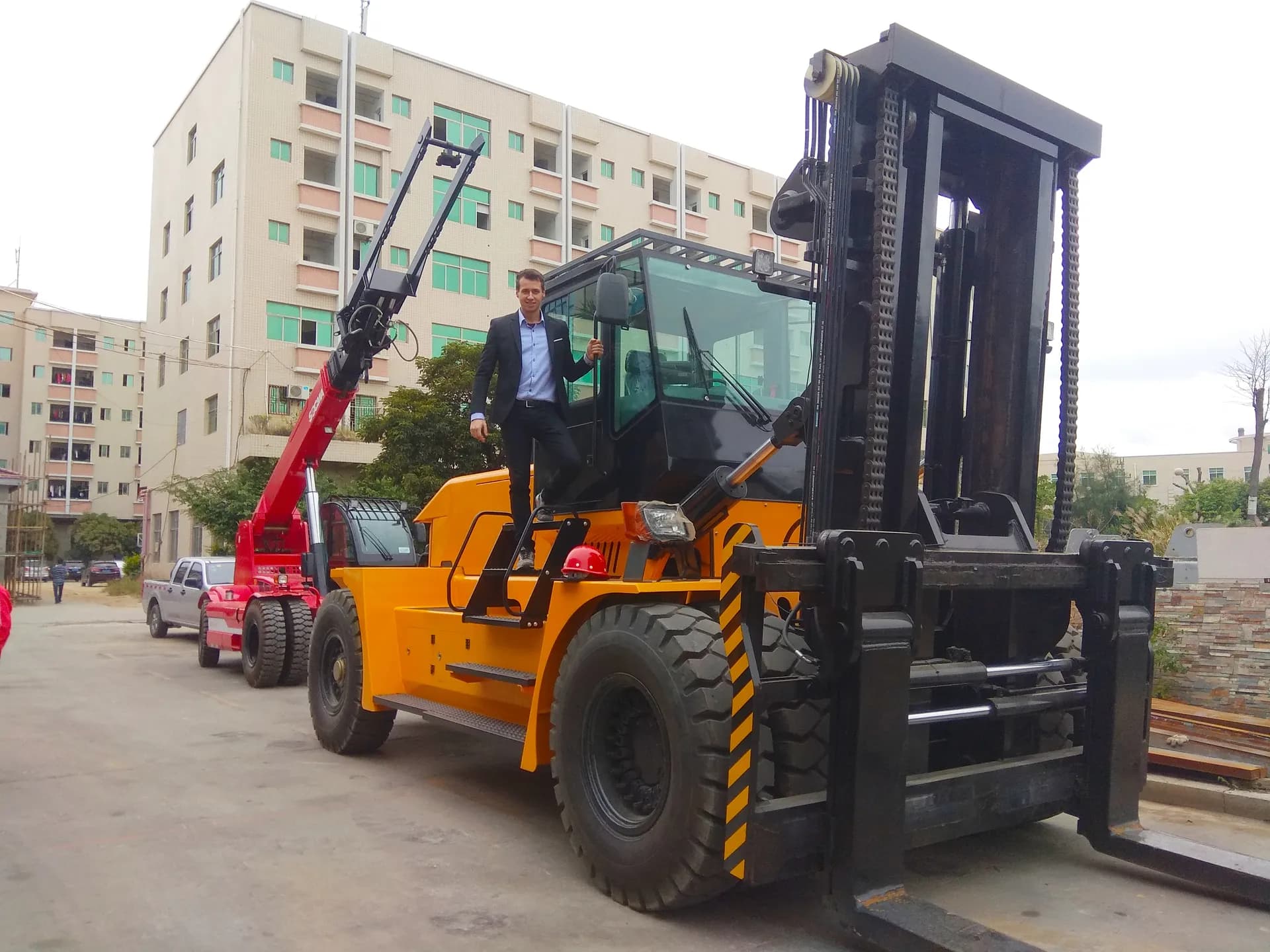 Michał Petza bei einem Besuch neben einem großen Gabelstapler in China